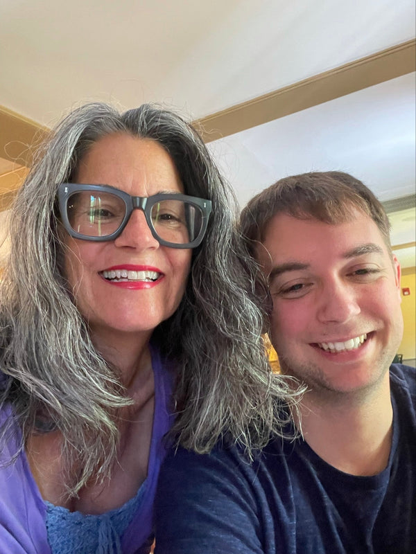smiling woman with glasses standing with her son also smiling