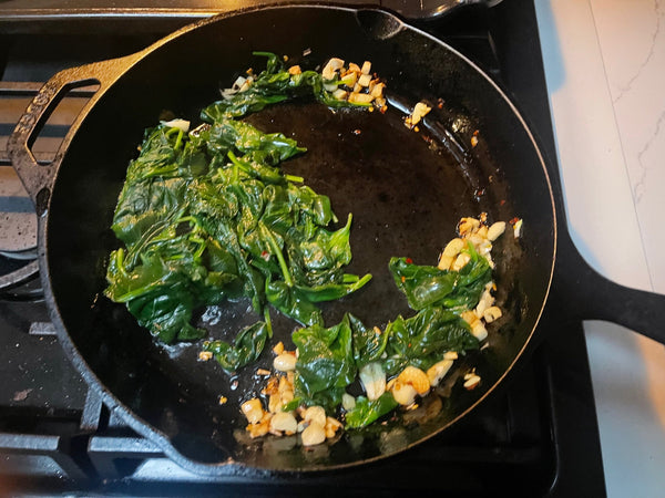 cast iron pan with sauteed spinach and garlic