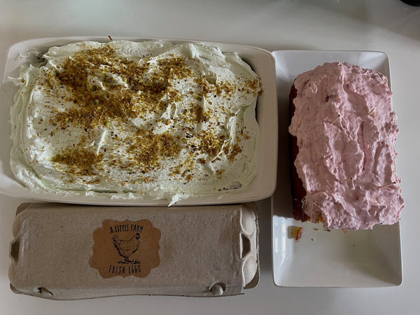 2 cakes, pistachio and lemon cake, both frosted and a dozen eggs in their carton from a local farm
