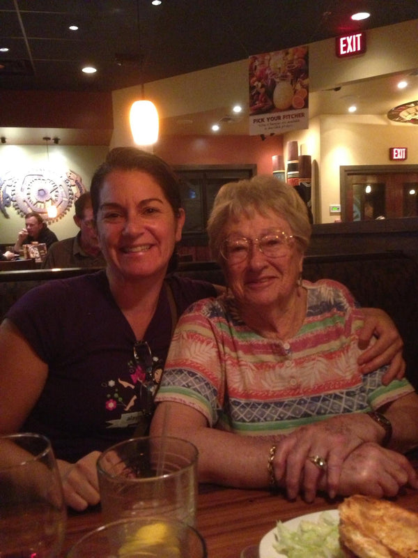 Two women sitting in a resturant, arms around each other.